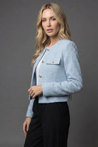 Side profile view of the light blue tweed jacket showing gold button closure and cropped waist length