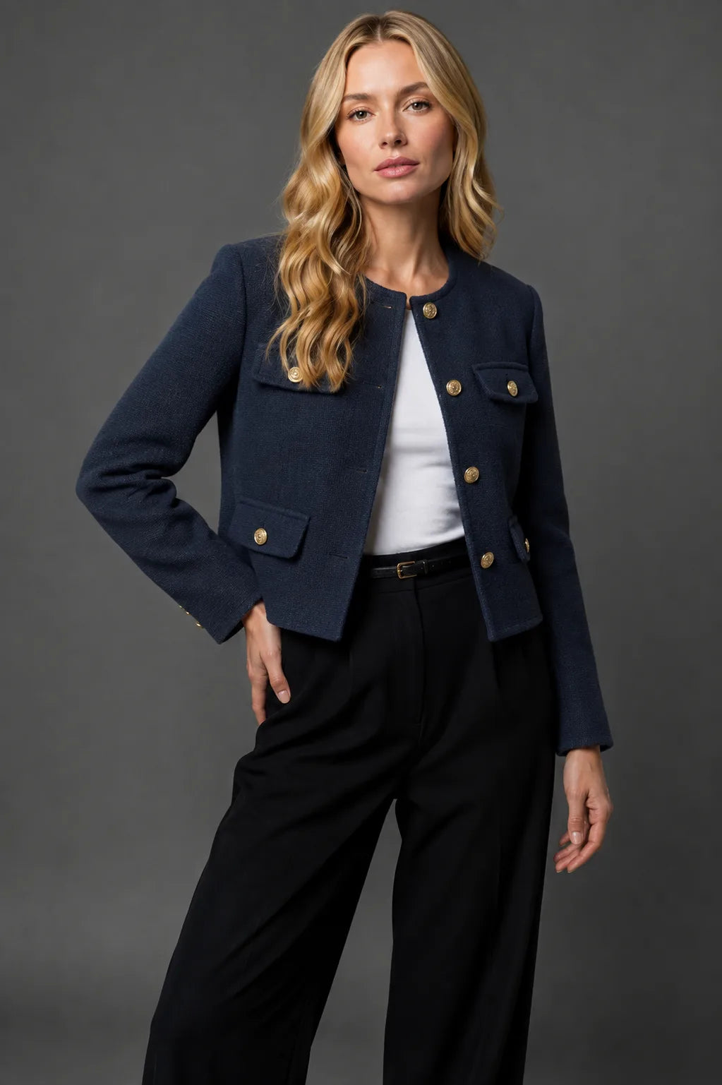 Navy blue tweed cropped jacket with collarless neckline and gold button fastening worn over a white top