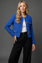 Front view of the light blue tweed jacket fully buttoned showing the rounded collarless neckline