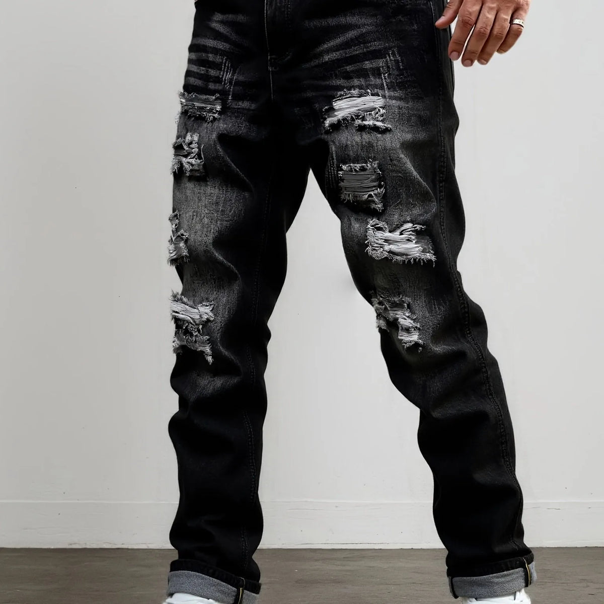 Front view of dark grey ripped straight-leg jeans styled with a turned-up hem and white trainers