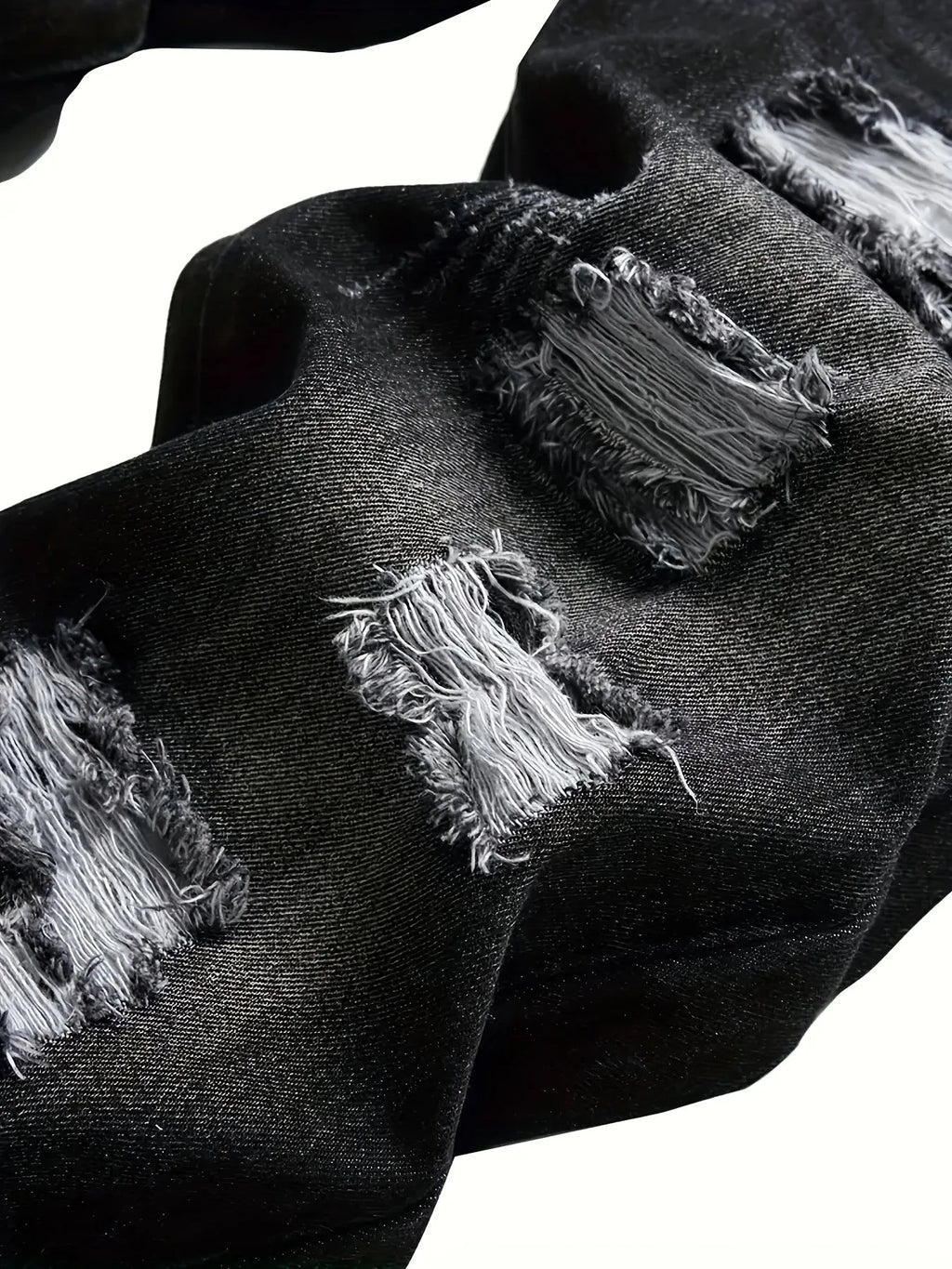 Close-up of frayed denim rips showing the exposed white thread detailing on dark grey fabric