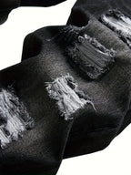 Close-up of frayed denim rips showing the exposed white thread detailing on dark grey fabric