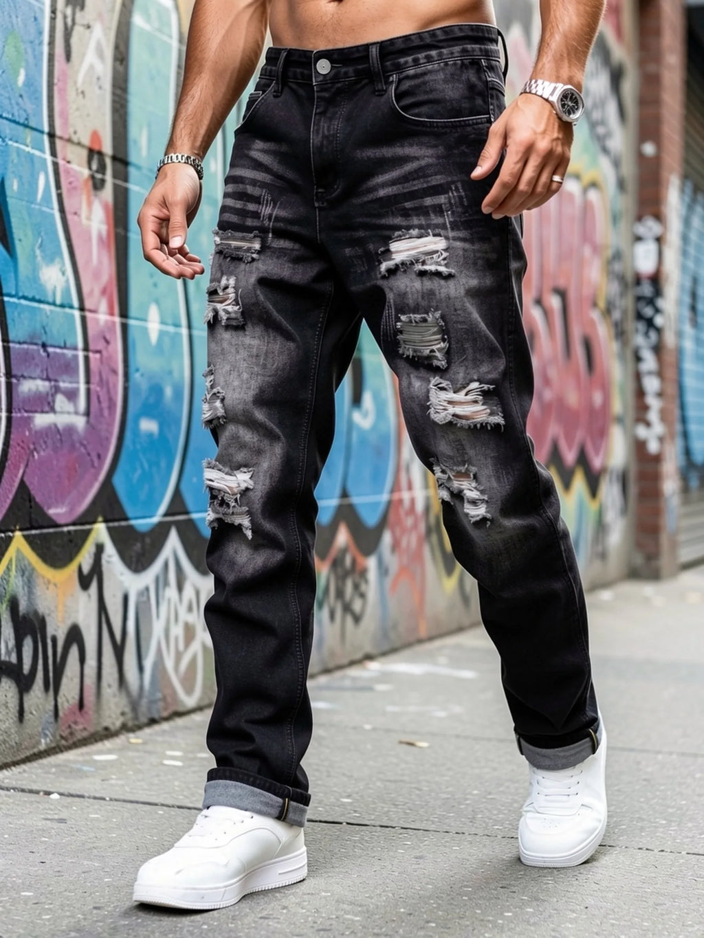 Front view of a model wearing dark grey distressed straight-leg jeans with rolled cuffs and trainers