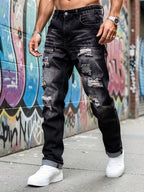 Front view of a model wearing dark grey distressed straight-leg jeans with rolled cuffs and trainers