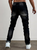 Back view of a model wearing dark grey ripped jeans showing the fit through the leg and rolled hem