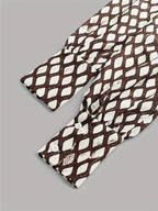 Close-up of the cuffed long sleeve showing the button fastening and the brown and cream print detail