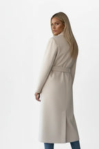 Back view of a woman in a beige longline coat, showing the belted waist and centre back vent
