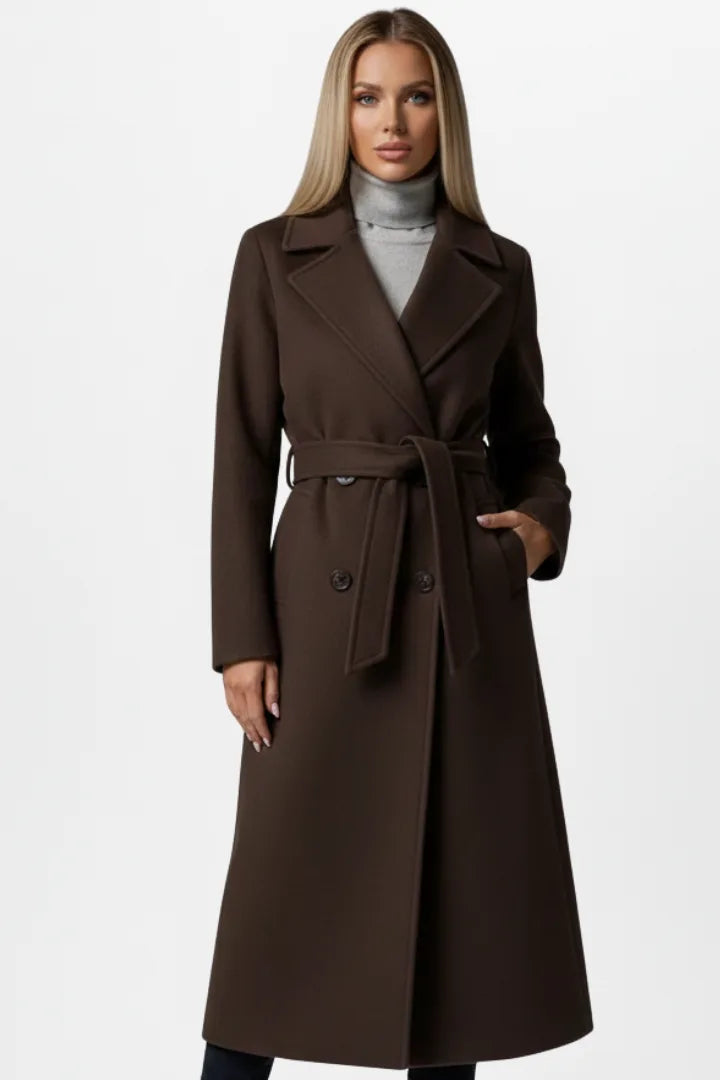 Front view of a woman wearing a chocolate brown double-breasted belted coat over a grey polo neck