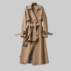 Beige double-breasted trench coat on a wooden hanger, belted waist, checked lining visible at the hem