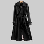 Black trench coat with notched lapel, wrap-style front and checked lining peeking through at the hem