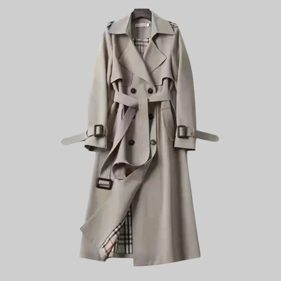 Grey trench coat shown fully buttoned with tie belt and buckled cuffs, midi length on hanger