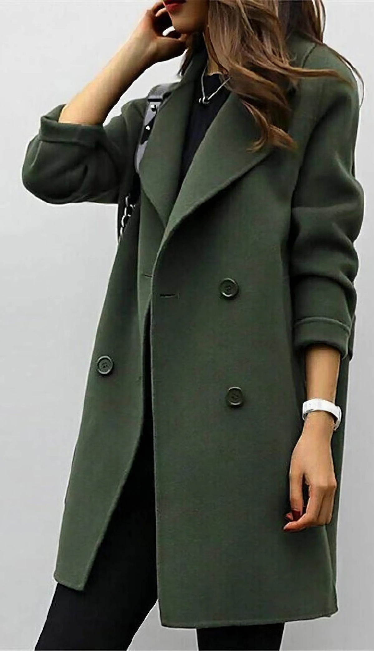 Close-up of green double-breasted wool coat with wide lapel and oversized button detail, worn over black outfit