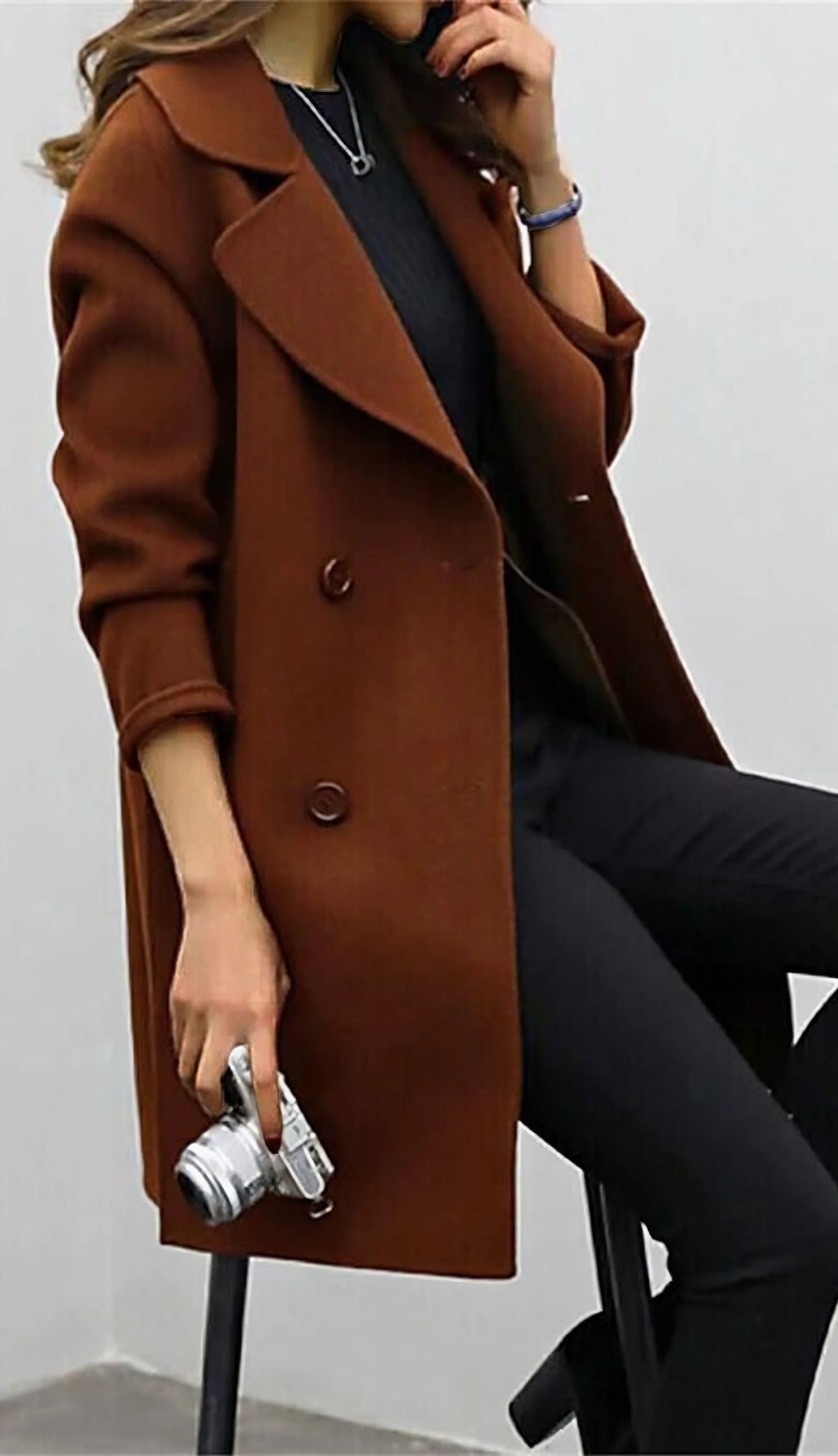 Side view of brown double-breasted wool coat showing rolled cuffs and button placement over a black top