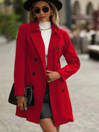 Front view of a woman wearing a red double-breasted trench coat with a black wide-brim hat and sunglasses