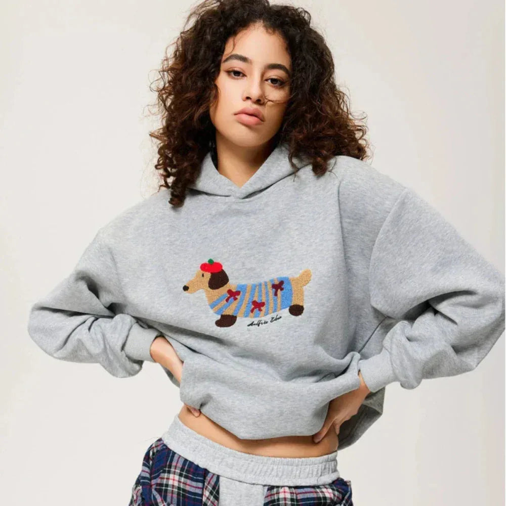 Woman wearing a grey marl hoodie with embroidered dachshund dog in a striped jumper and beret, front view