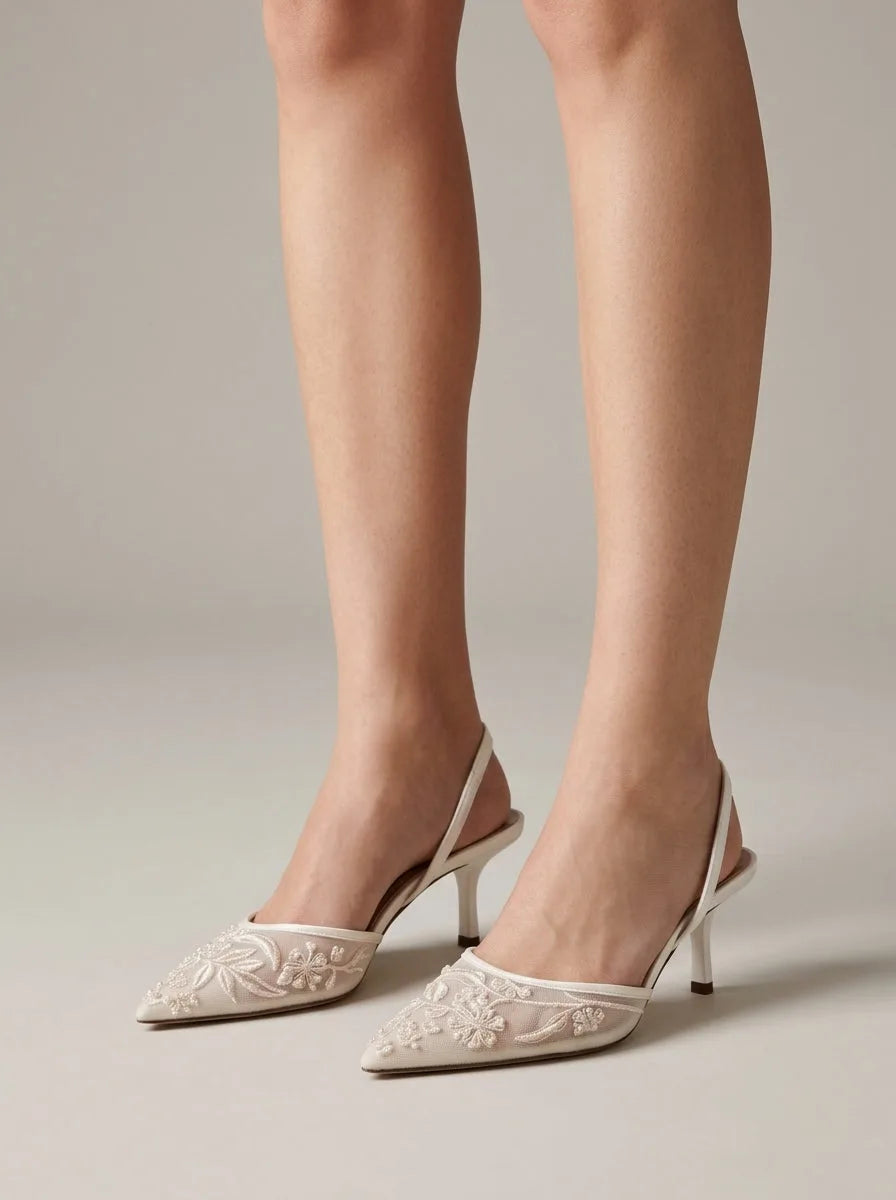 Side view of ivory slingback kitten heels with sheer mesh vamp and pearl floral embroidery, worn while standing