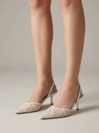 Side view of ivory slingback kitten heels with sheer mesh vamp and pearl floral embroidery, worn while standing