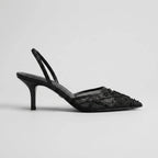 Studio side profile of a black mesh pointed toe kitten heel with beaded floral embroidery and slingback strap