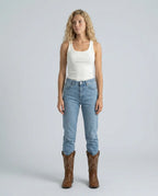 Woman wearing light wash denim jeans with brown embroidered cowboy boots in a full-length standing pose