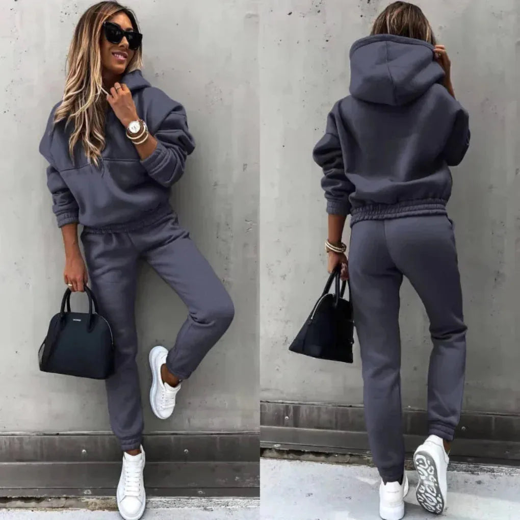 Dark grey hooded tracksuit shown from the front and back, highlighting the relaxed drop-shoulder fit and side pockets