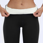 Close-up of a fleece-lined waistband being pulled forward, showing the soft white fleece interior against black outer fabric