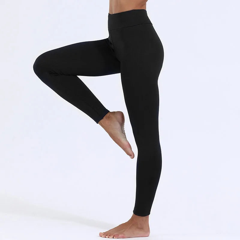 Side profile of a woman wearing black high-waisted leggings, standing on one leg, barefoot