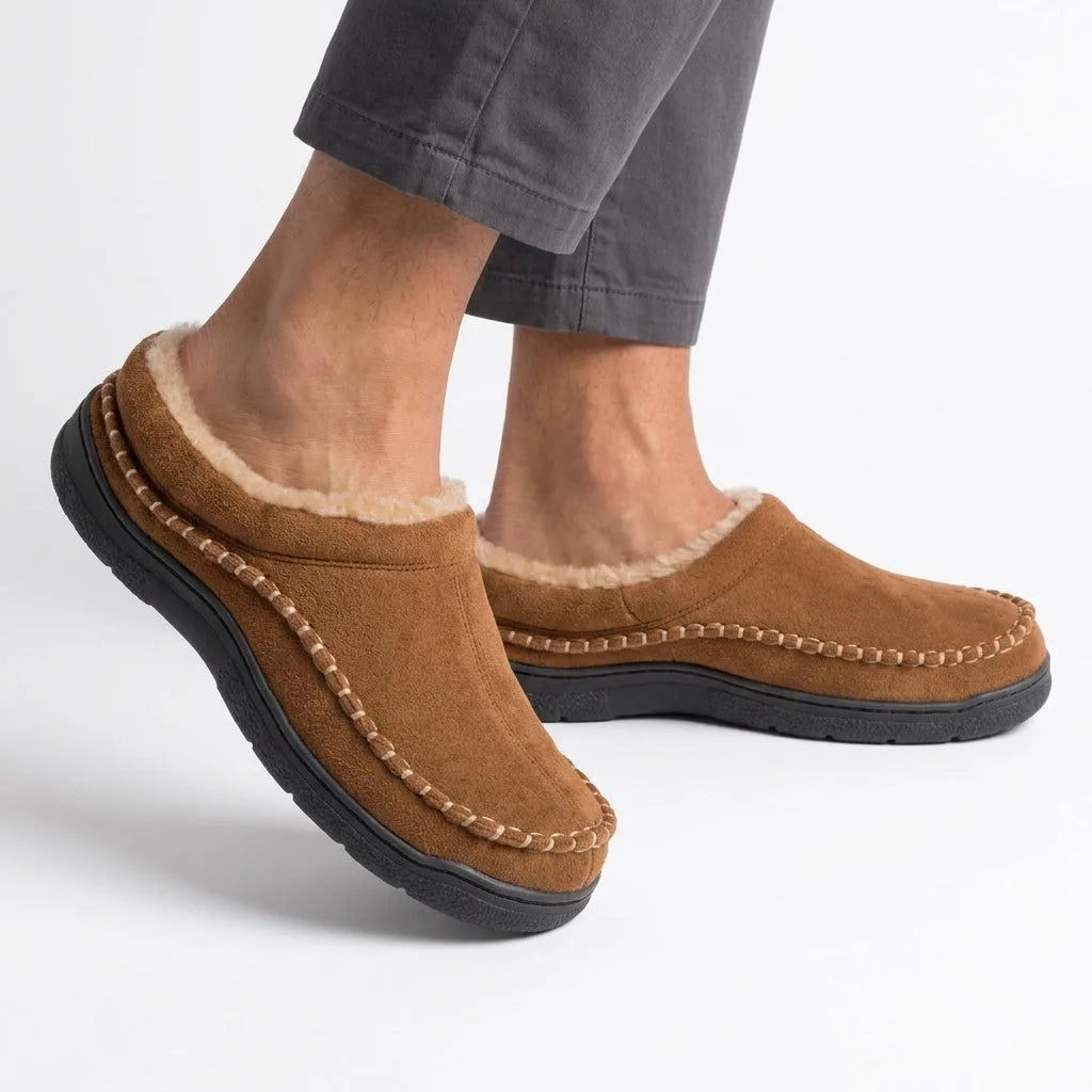Side view of a man wearing a tan slip-on clog slipper, showing the fleece collar at the ankle