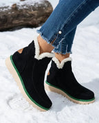 Black suede ankle boots with cream fur lining and tan heel patch, styled with denim jeans in the snow
