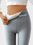 Grey thermal leggings pulled open at waist revealing thick white fleece lining and flat seam stitching