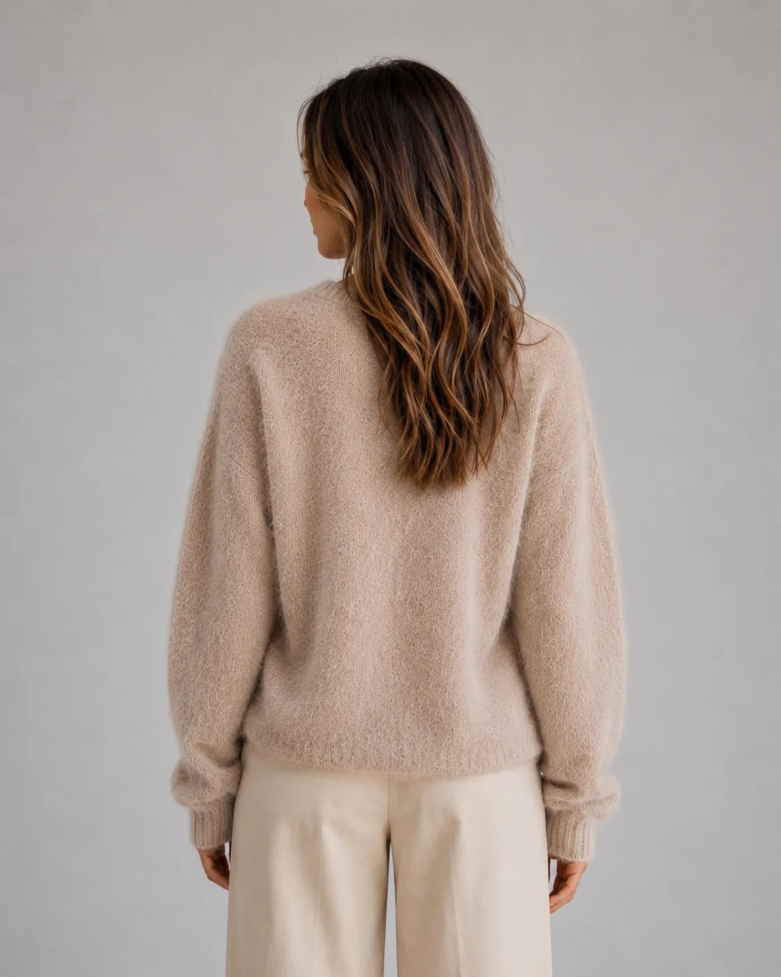 Back view of the beige fluffy knit cardigan showing relaxed drop shoulders and ribbed cuffs