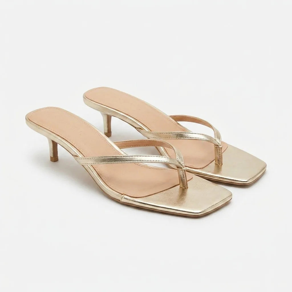Pair of gold thong-strap kitten heel sandals with square toe and slim heel, shown from a front angle on a white background