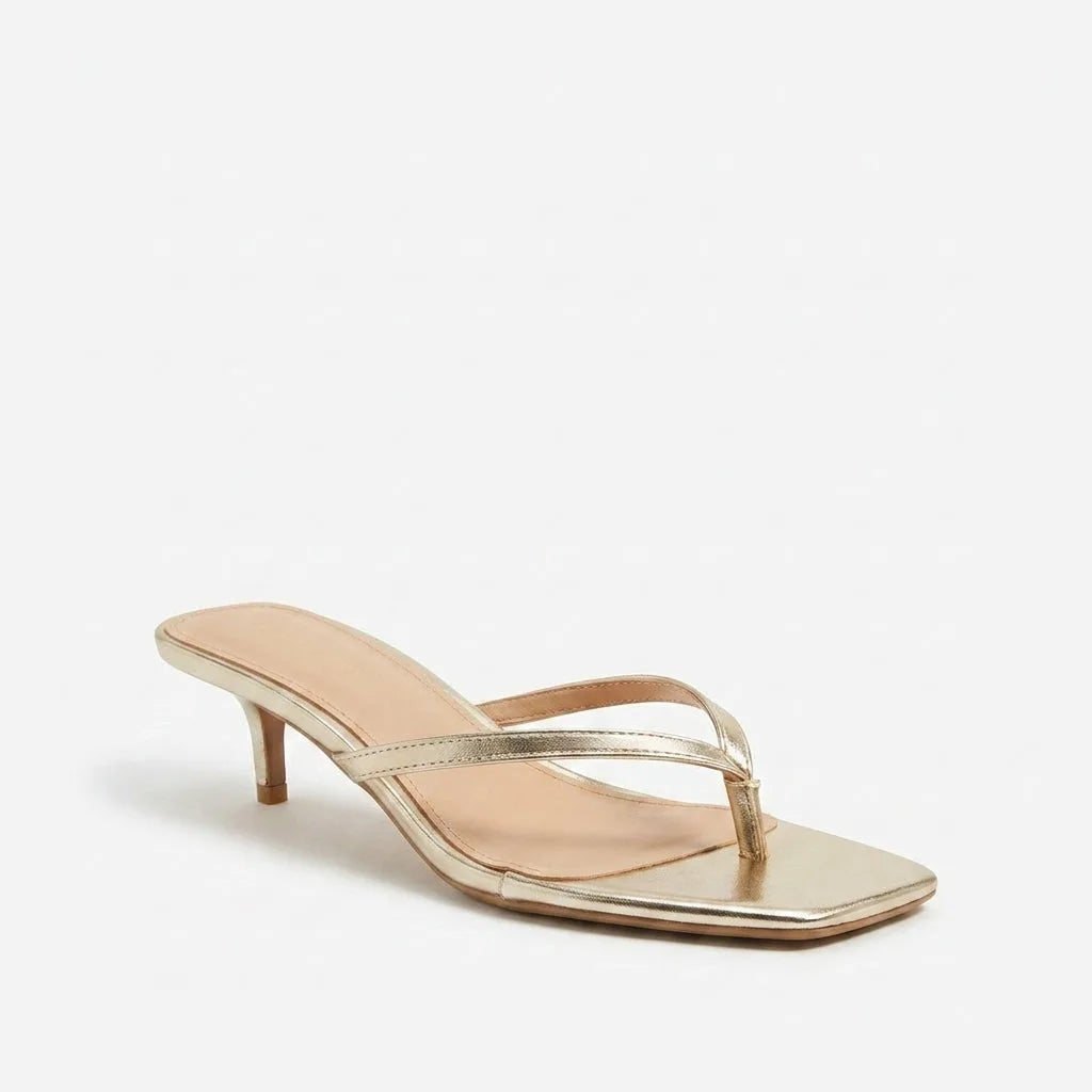 Single gold kitten heel sandal in profile, showing the slender heel, square toe and thin strappy design