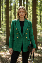Front view of a green checked tweed double-breasted blazer with gold buttons, worn over a black top in a forest setting.