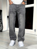 Front view of grey denim jeans on model with hands in pockets, showing regular fit and washed finish