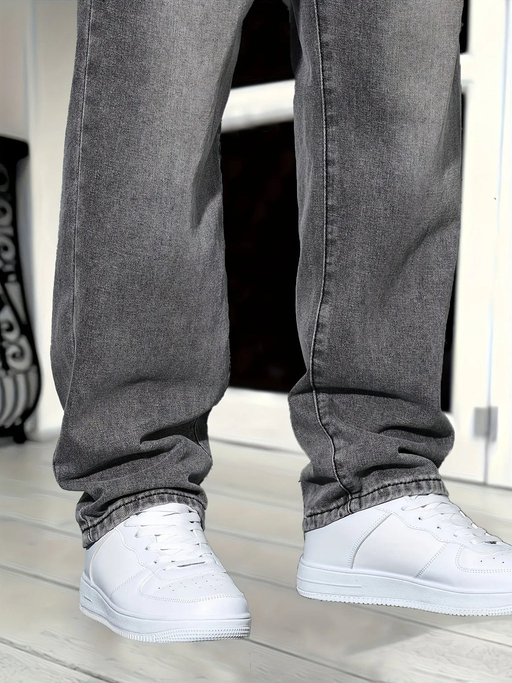Close-up of lower leg hems showing washed grey denim texture and fit over white trainers
