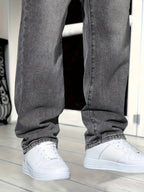 Close-up of lower leg hems showing washed grey denim texture and fit over white trainers
