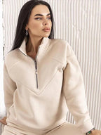 Close-up of a beige half-zip fleece top showing the raglan sleeve seams and metal zip pull detail.