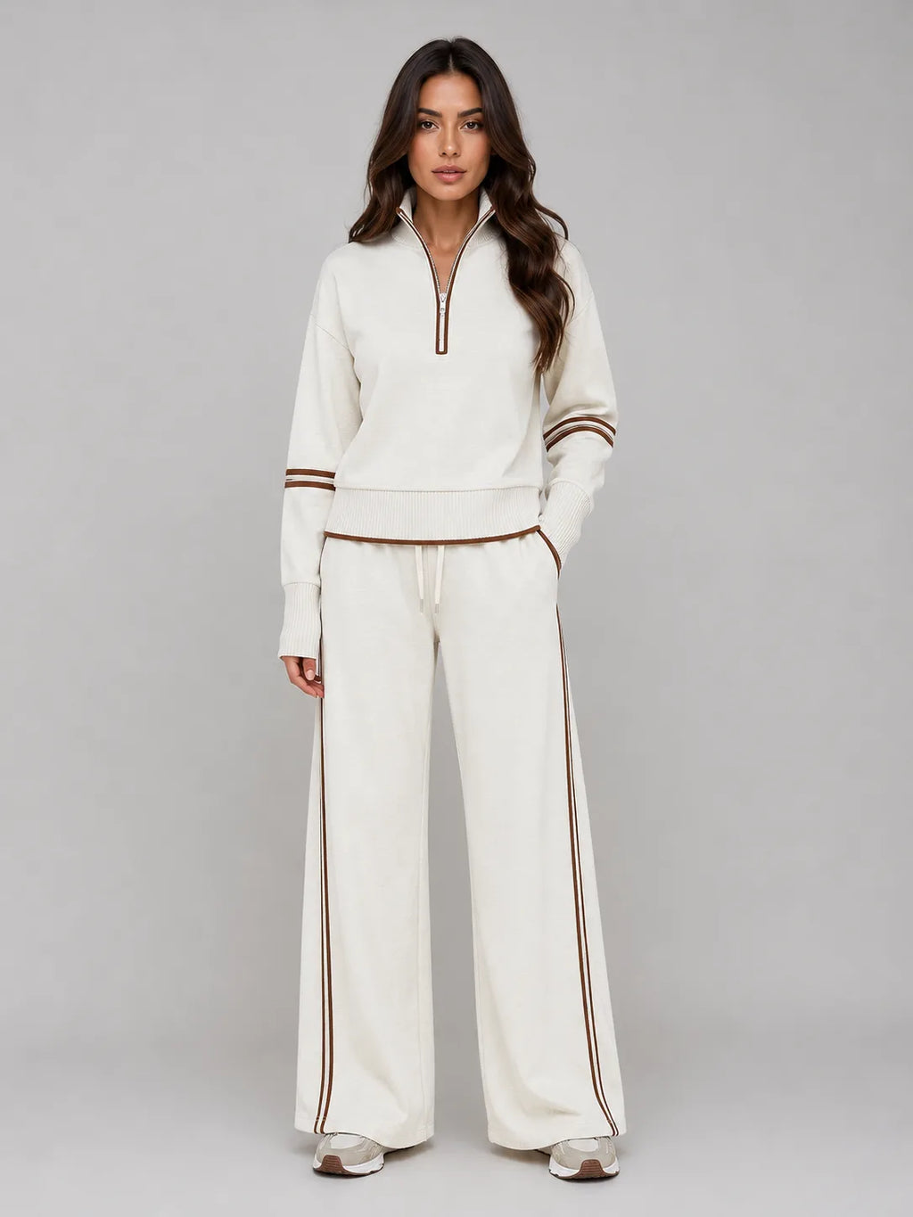 Front view of woman wearing cream half zip lounge sweatshirt and wide leg trousers with brown stripe trim