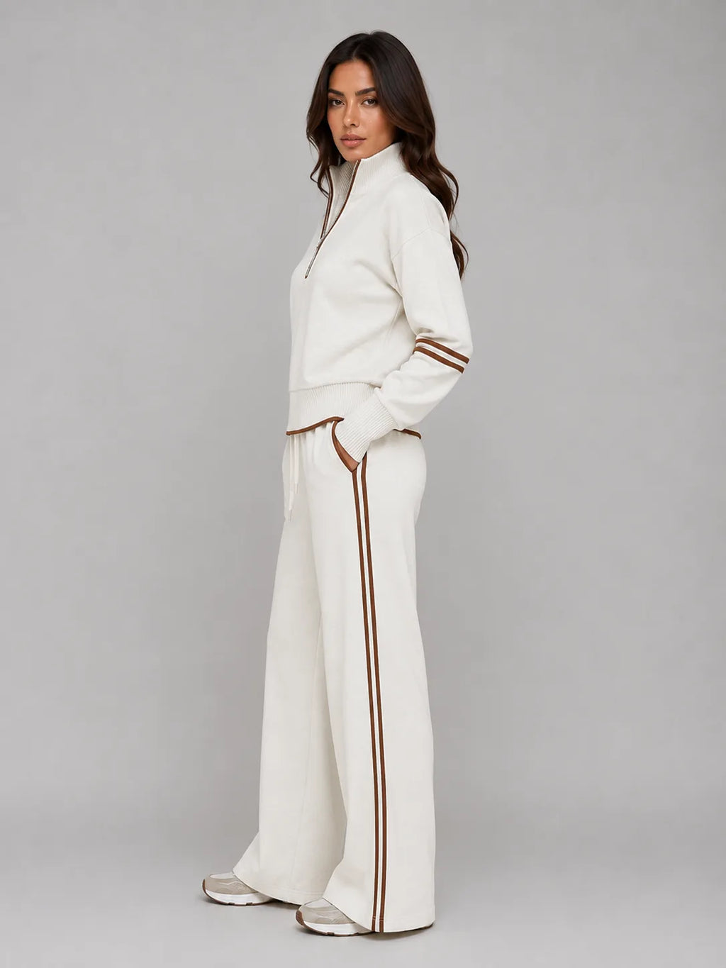 Side profile of woman in cream lounge set with hands in trouser pockets, showing relaxed wide leg fit