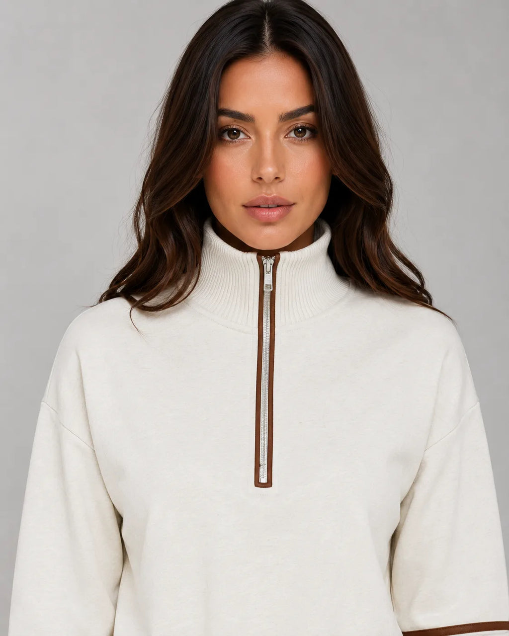Close-up of cream half zip funnel neck collar with silver zip and brown piping detail