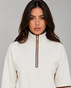 Close-up of cream half zip funnel neck collar with silver zip and brown piping detail