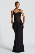 Front view of a black halter-neck evening gown with sheer mesh bodice and draped ruched skirt falling to the floor