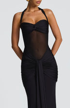 Close-up of the black dress's twist-front bust, sheer mesh midriff and gathered draped skirt detail