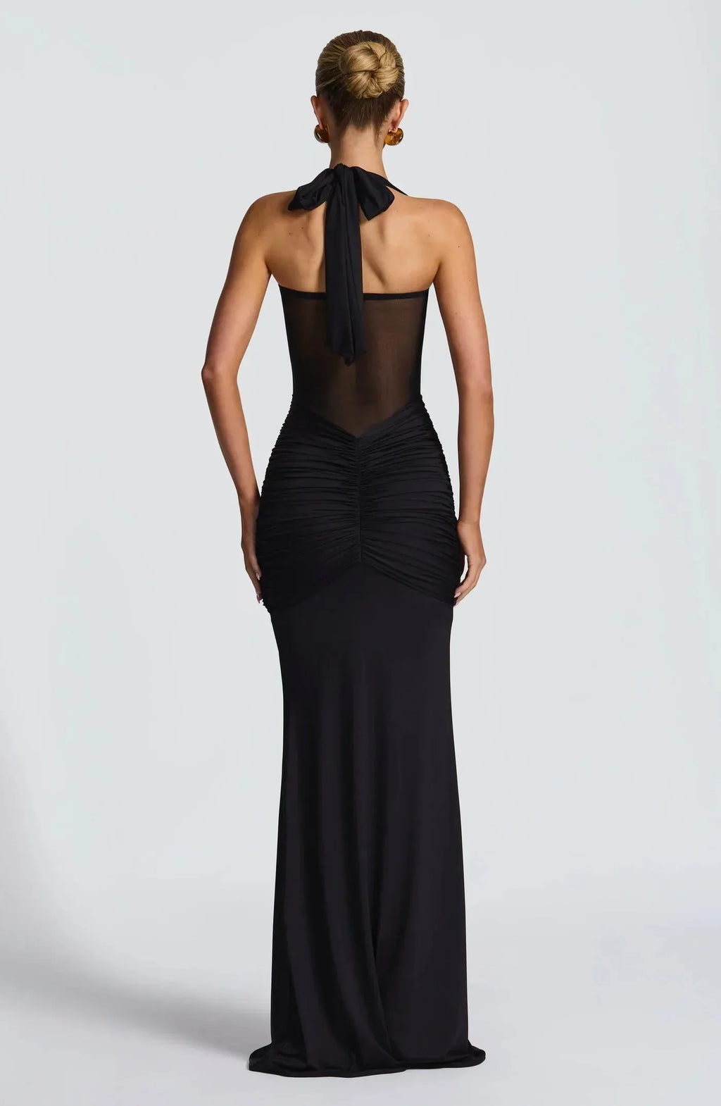 Back view of the black gown showing the tied halter strap and ruched fabric cascading down the skirt
