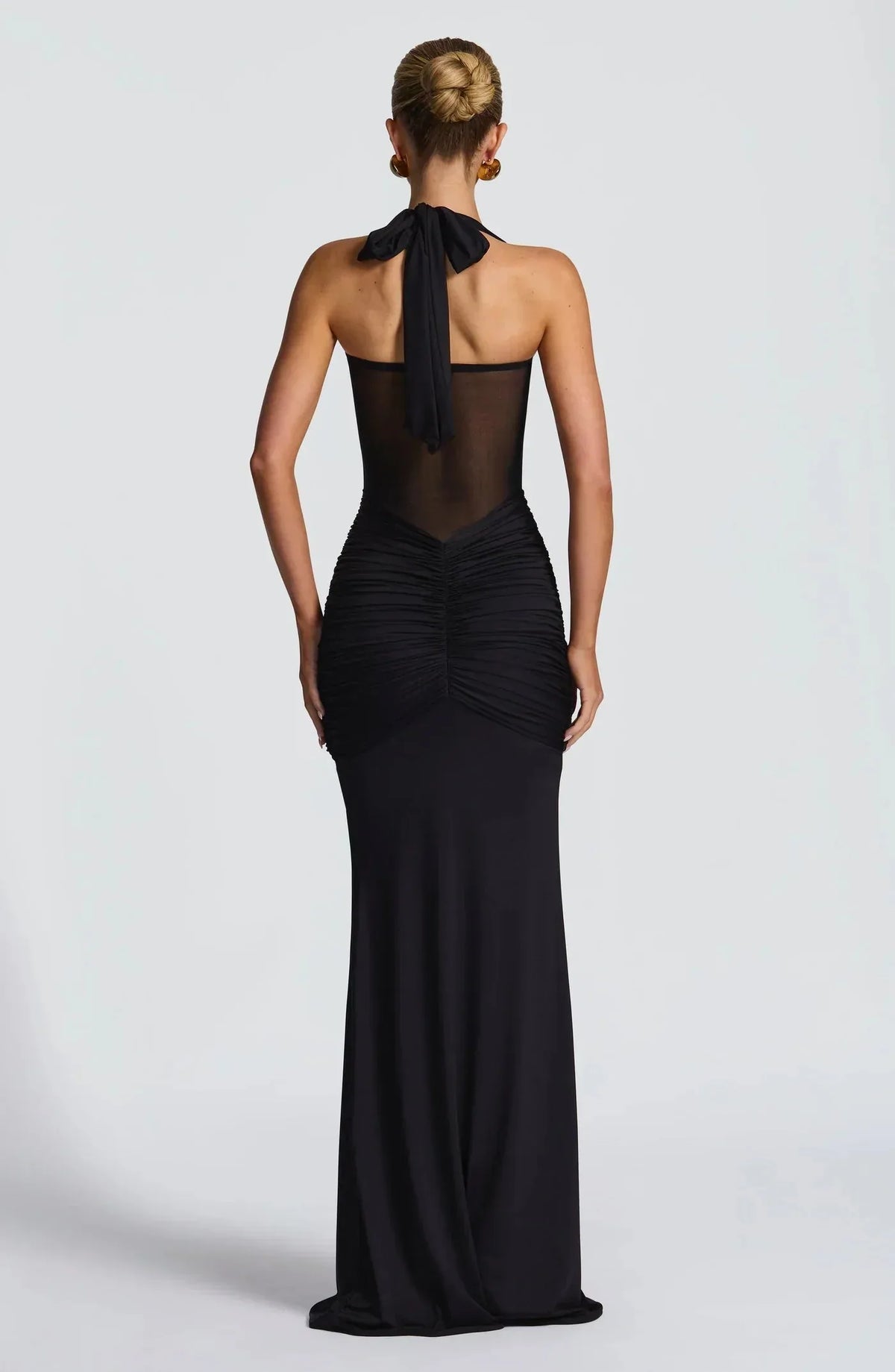 Back view of the black gown showing the tied halter strap and ruched fabric cascading down the skirt