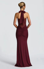 Model wearing the burgundy halter evening dress paired with gold hoop earrings and a statement bangle