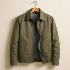 Olive green harrington jacket on wooden hanger, point collar and welt side pockets visible