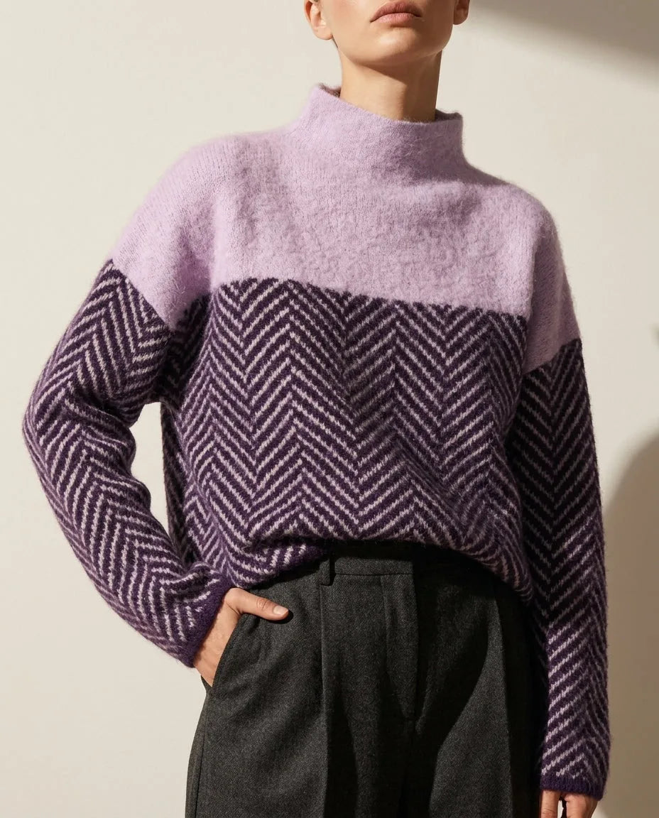 Close-up of a lavender mock neck jumper with a navy and cream herringbone knit panel across the chest and sleeves