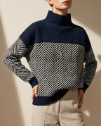 Navy mock neck jumper with a contrasting cream and navy herringbone knit on the body and sleeves, paired with linen trousers