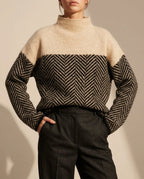 Camel mock neck jumper with a black and cream herringbone knit panel, worn with charcoal tailored trousers